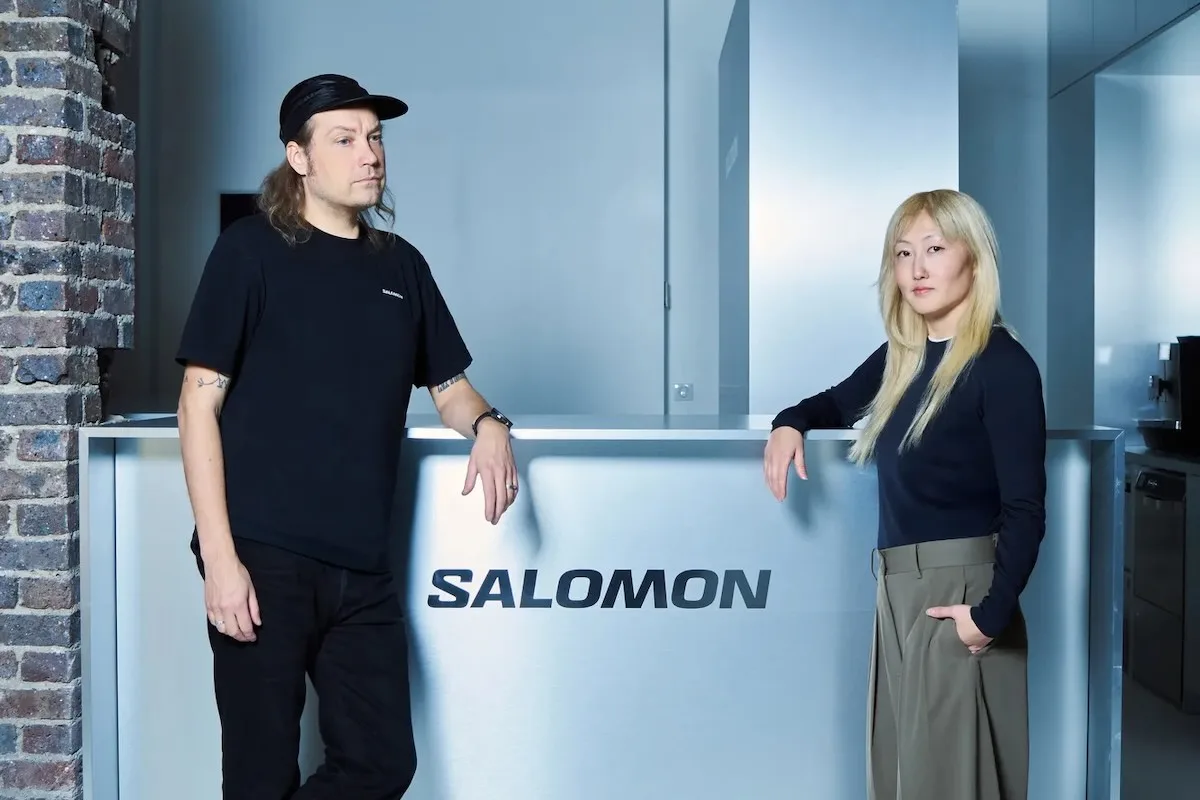Креативна команда Salomon - жінка та чоловік стоять в офісі Salomon Paris за стійкою реєстрації з логотипом бренду