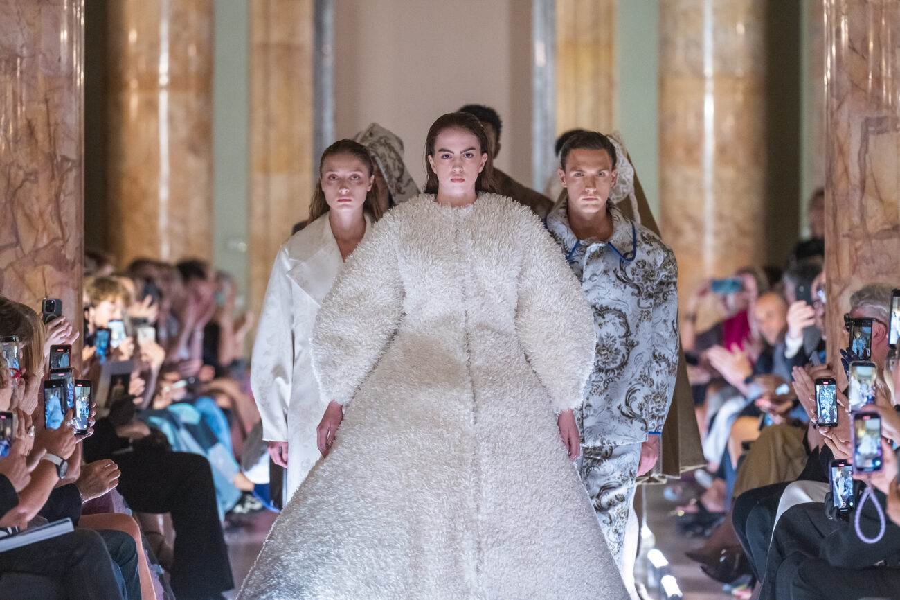 Творіння Марлени Кравчик. Моделі на подіумі, зокрема модель на передньому плані у великій хутряній сукні.
