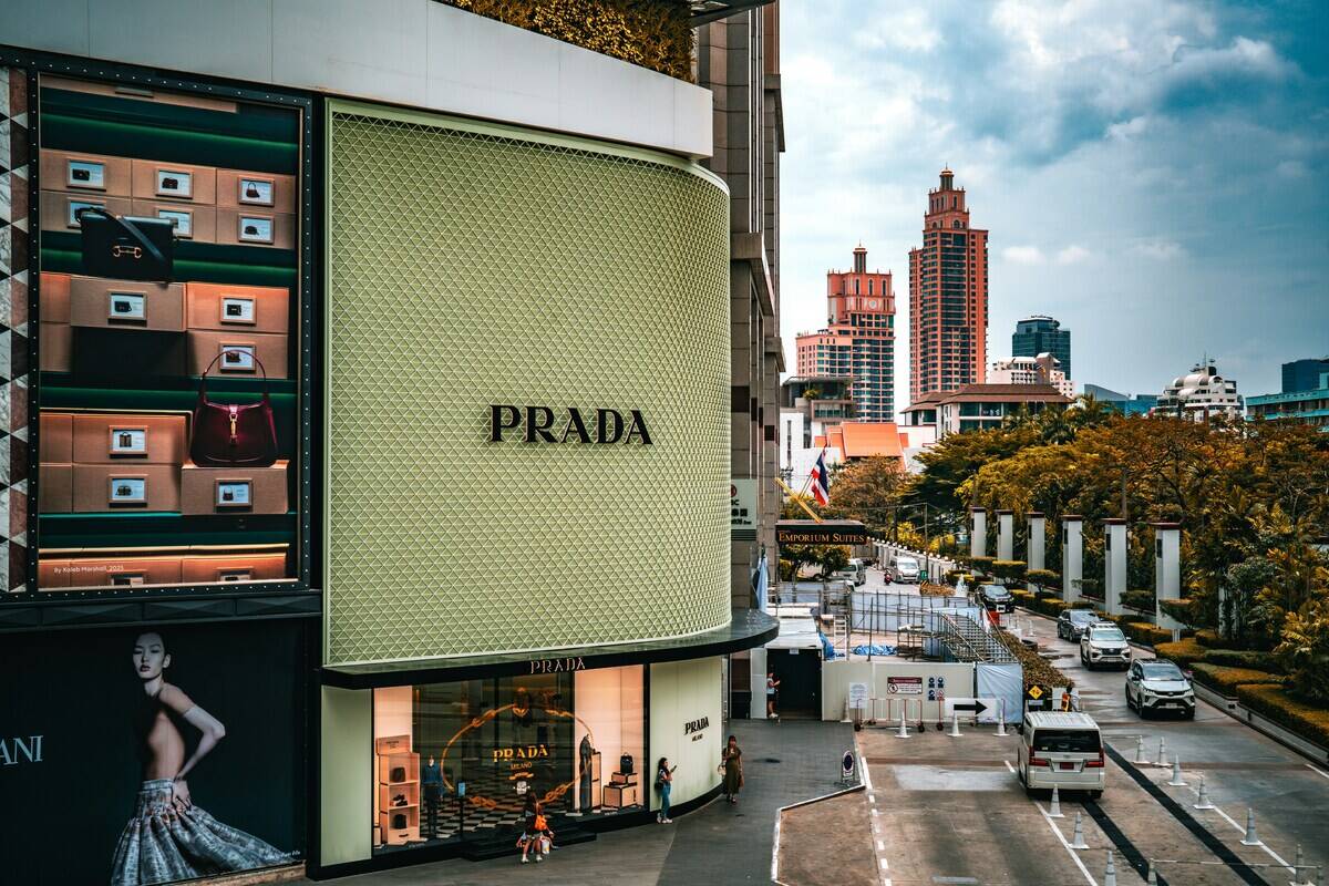 Партнерство з постачальником Prada завершується. Сучасний магазин Prada в кутовій будівлі в центрі міста, з елегантною вітриною та логотипом бренду на тлі жвавої вулиці та високих міських хмарочосів.