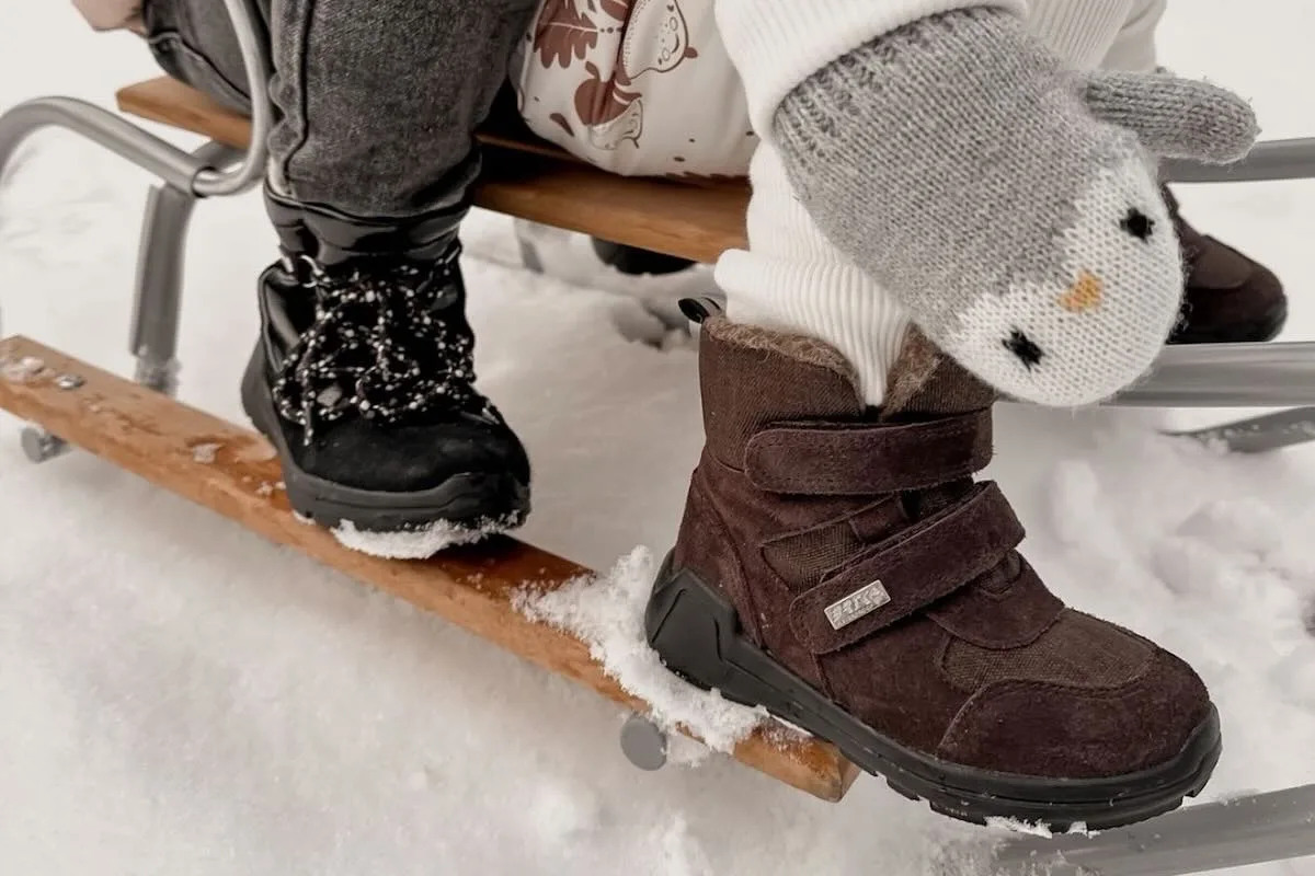 Польський виробник взуття Bartek SA банкрутує. Що далі? На фото крупним планом зображено дитяче взуття, яке катається на санчатах по снігу.