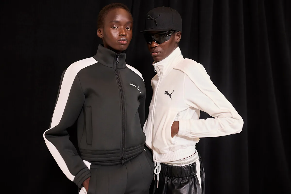 Придбання Puma компанією Anta Sports. Двоє людей у спортивній формі Puma – одна в чорно-білому, інша в чорно-білому спортивному костюмі – позують перед чорною завісою.