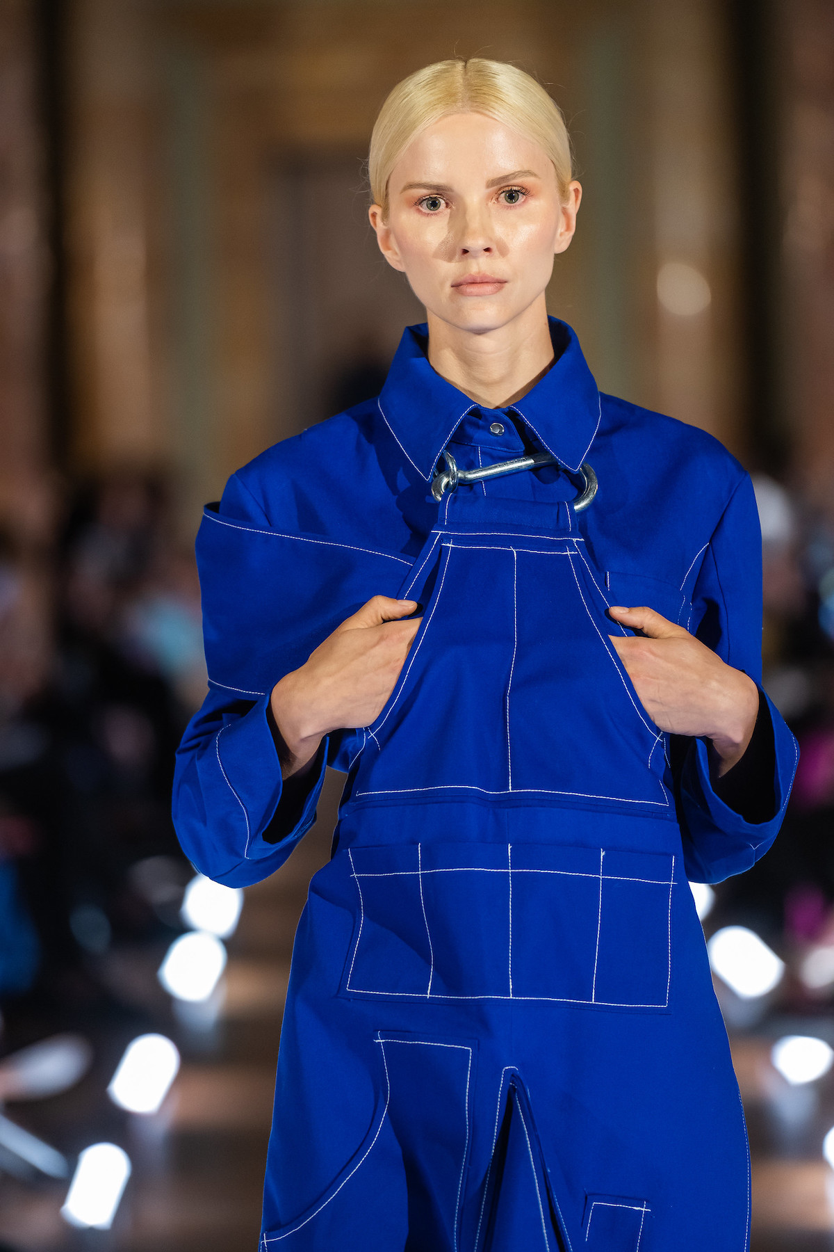 East Bound Roma – польський показ мод у Римі: модель у насичено-синьому комбінезоні з контрастною строчкою та металевою пряжкою йде подіумом.