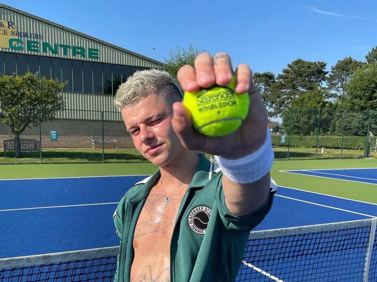 Олексій Гамблін Slazenger Generation Z. Молодий чоловік на тенісному корті тримає тенісний м'яч із написом