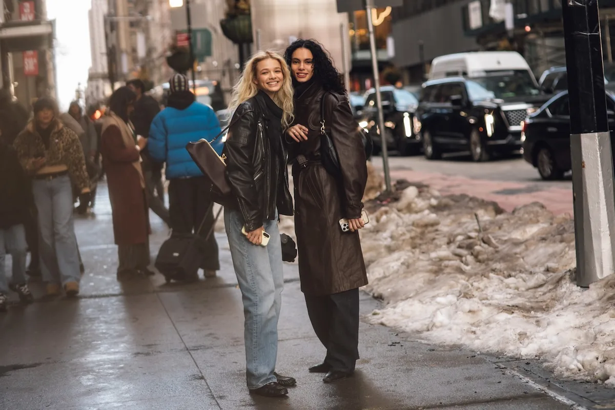 Поглинання Depop компанією eBay. Дві жінки вуличного стилю у шкіряних куртках та пальтах на засніженій міській вулиці.