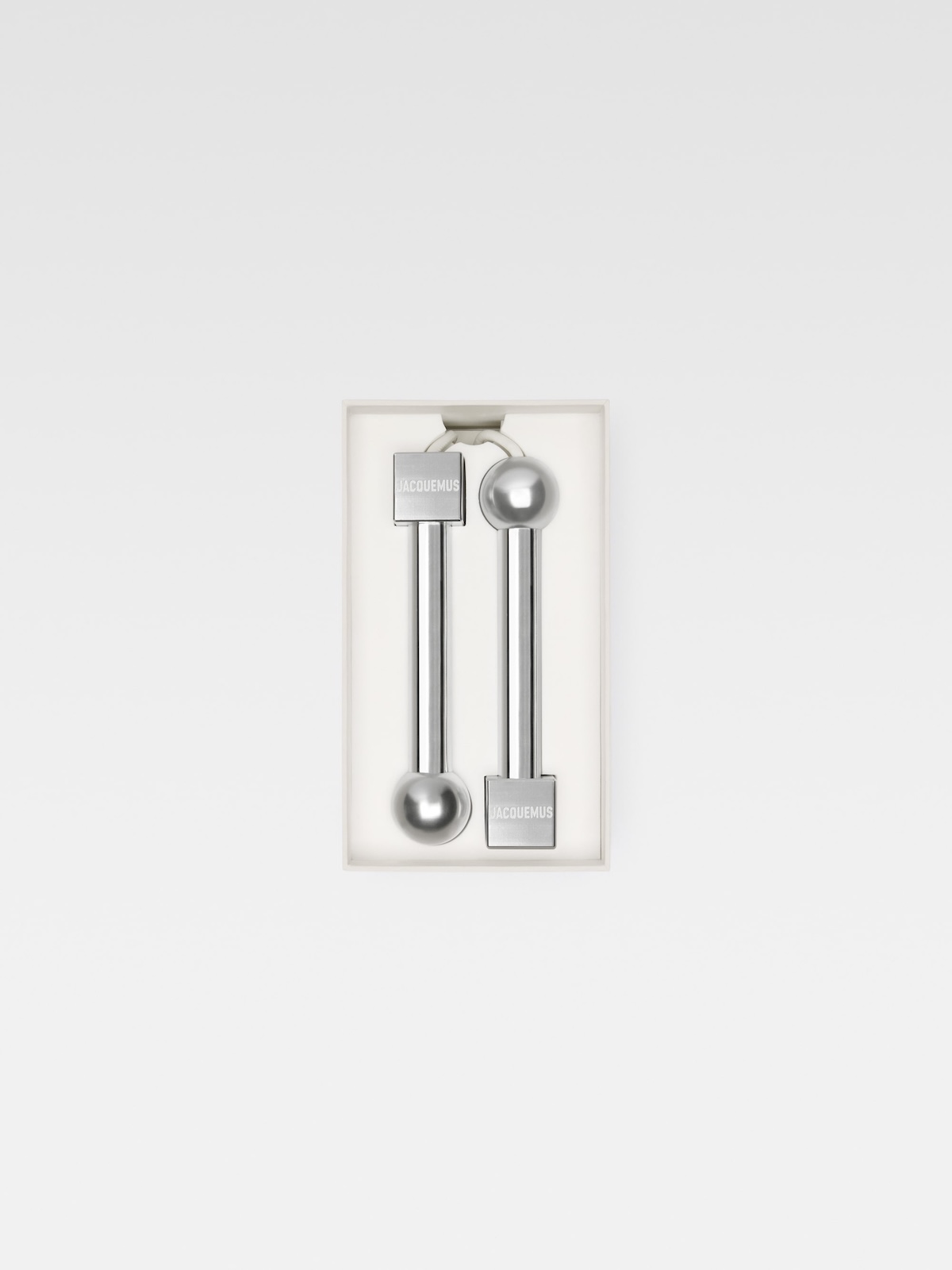 Металева скакалка Jacquemus з циліндричними ручками, упакована в прямокутну коробку.