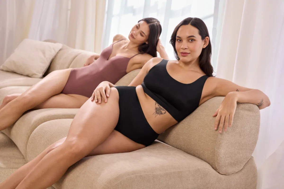 Реструктуризація компанії Lycra. Дві жінки в облягаючій еластичній спідній білизні сидять на дивані в світлому інтер'єрі.