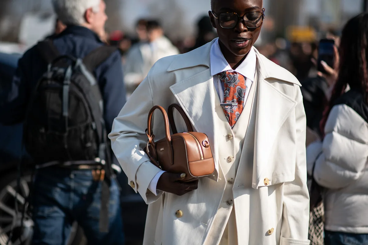 Людина з елегантною сумочкою на людній вулиці – образ зростаючого потоку покупців, який може посилитися через обмеження на недільний шопінг.