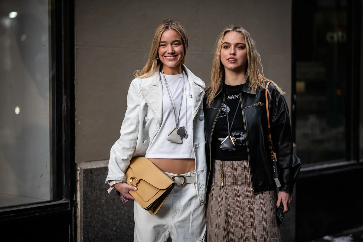 ЄС штрафує платформи електронної комерції. Дві жінки у модному вуличному одязі з дизайнерськими сумками сфотографовані на міській вулиці. Фото ілюструє тему електронної комерції та імпорту дешевих товарів до ЄС, що може підпадати під нові правила та додаткові збори.