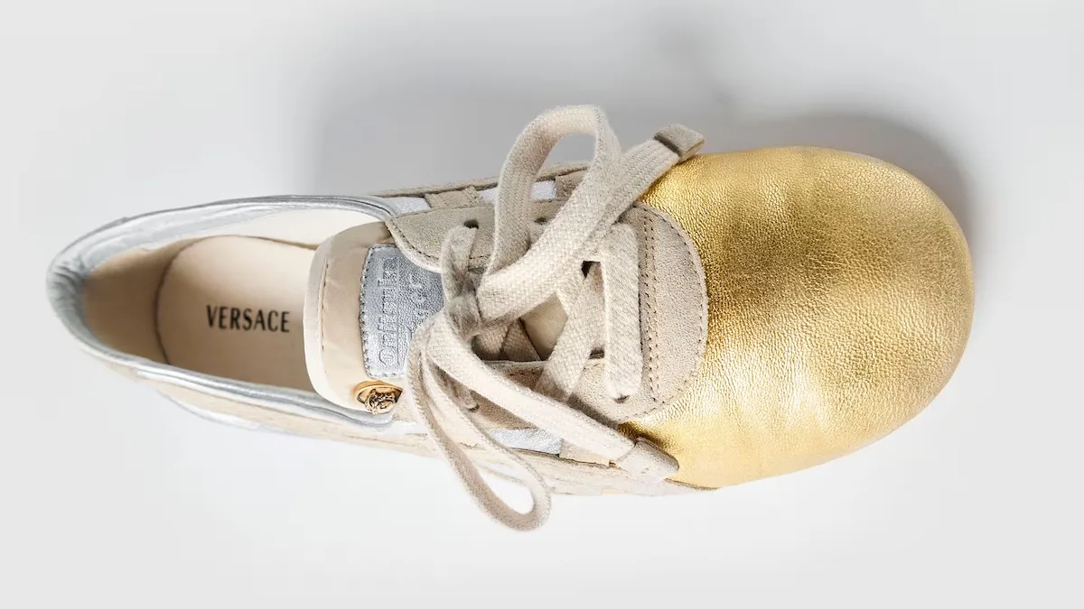 TAI-CHI Sakura має металевий золотий носок та світлий верх із замші та шкіри. Витончені деталі Versace та мінімалістична форма підкреслюють розкішний характер дизайну.