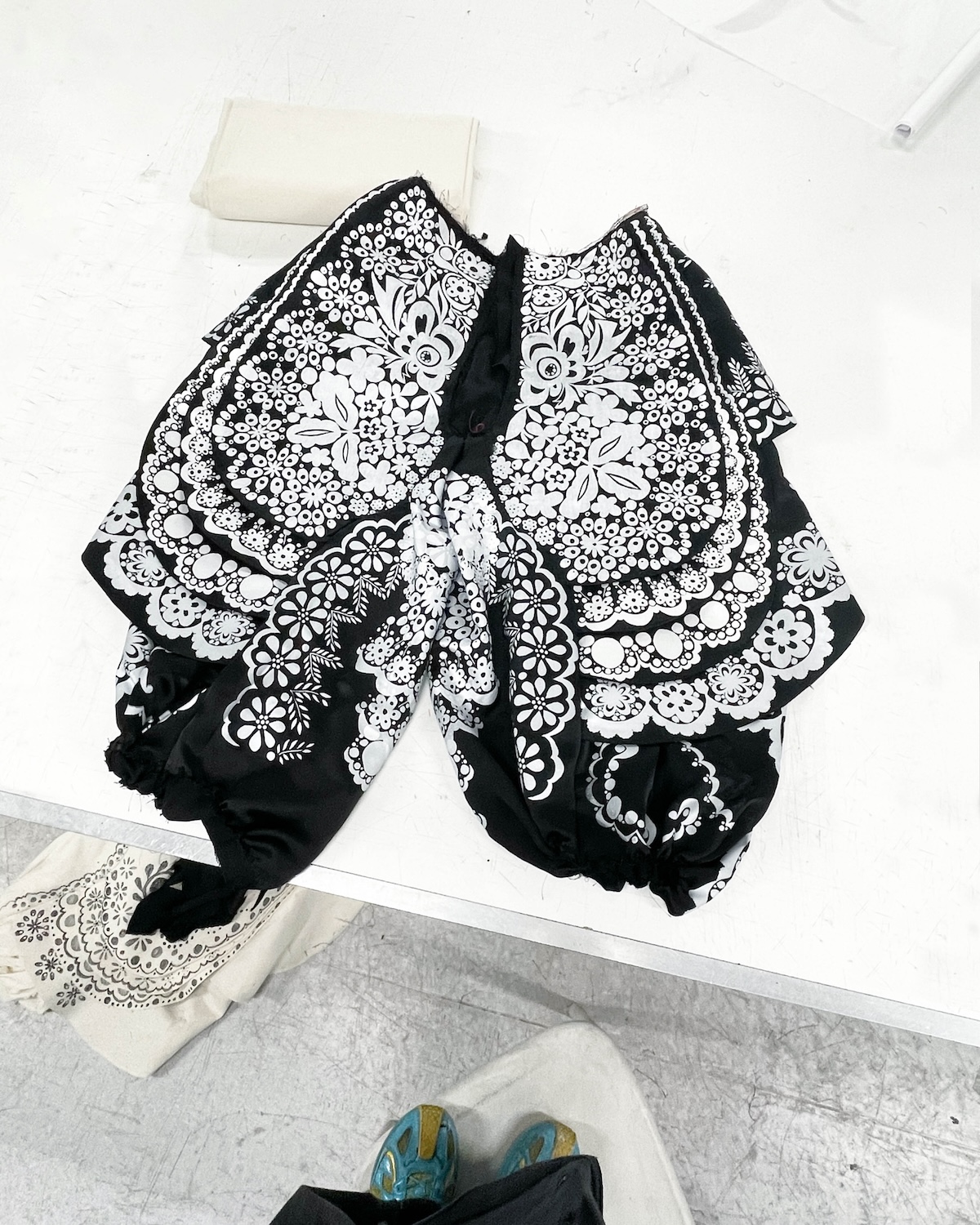 Уривок дизайну з випускної колекції Губерта Пельца, натхненний польським фольклором. Чорно-білі штани, прикрашені багатим орнаментальним принтом, нагадують традиційну народну вишивку. Проєкт демонструє, як молодий дизайнер інтерпретує майстерність у сучасній моді.