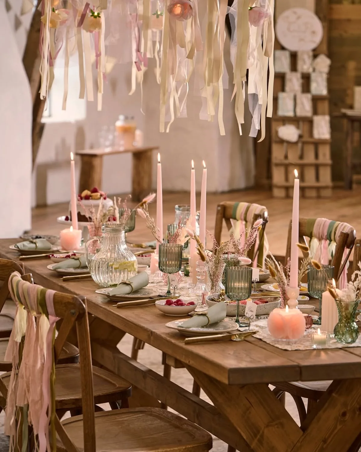 Пастельна скандинавська композиція столу – дерев'яний стіл з декором, свічками, скляним посудом та текстильними прикрасами у відтінках рожевого та бежевого.