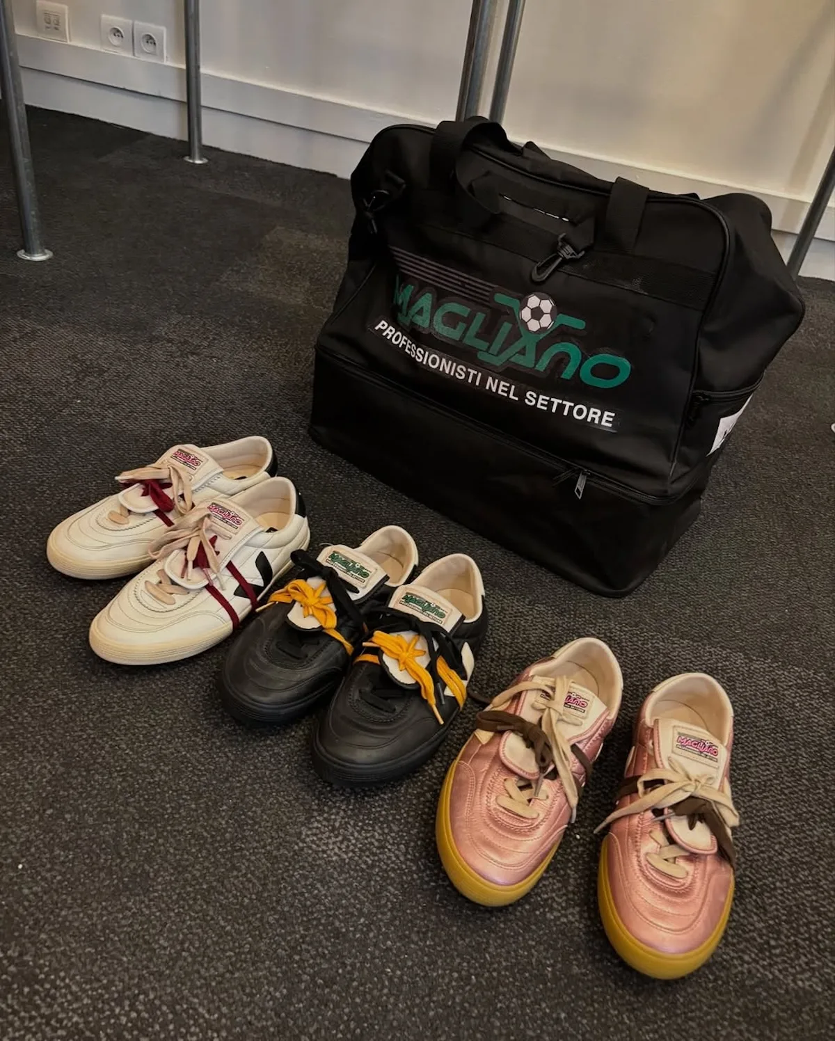 Veja x Magliano. Три пари ретро-кросівок у стилі футбольного кор-лайфстайлу розташовані поруч зі спортивною сумкою, естетика натхненна трендами кросівок весни 2026 року.