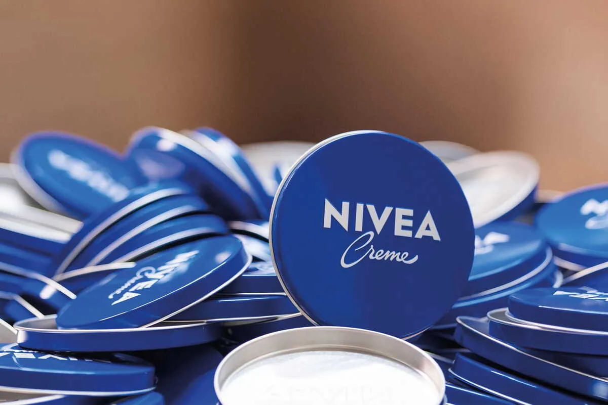 Культове пакування крему Nivea у синіх металевих банках, складених стопкою. На зображенні зображено один із найвідоміших продуктів компанії, яку відомство оштрафувало за прострочення платежів підрядникам.