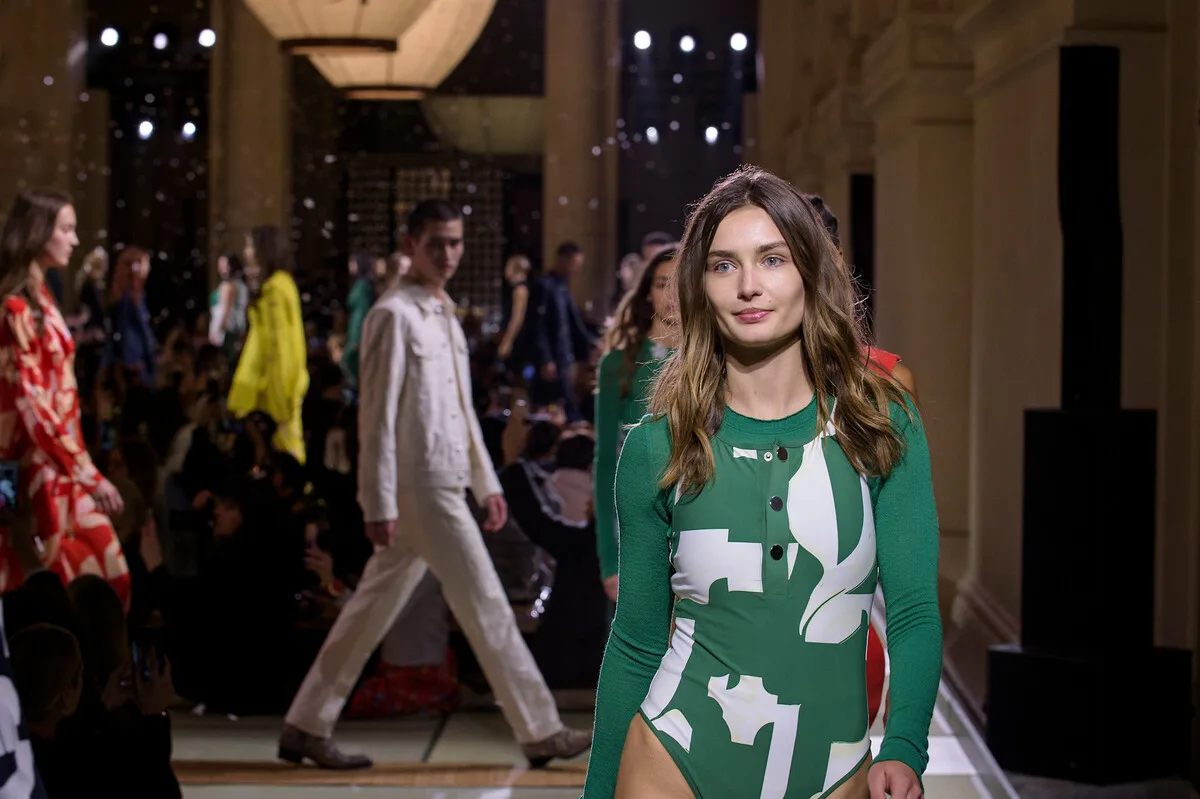 Сталий розвиток H&M 2025. Модель йде подіумом під час показу мод H&M Group, демонструючи колекцію в сучасному просторі. Фото натякає на трансформацію галузі, де навіть швидка мода починає поєднувати стиль із кліматичними амбіціями.