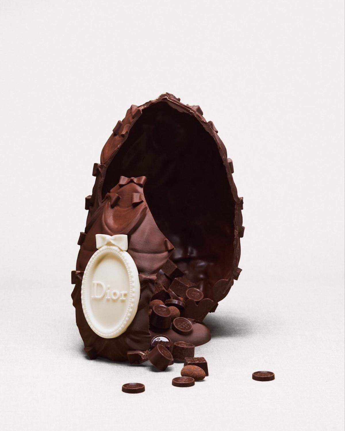 Розкішне пасхальне яйце від Dior з декоративним медальйоном та шоколадними елементами всередині. Художній десерт до Великодня 2026 року, що поєднує високу моду з кондитерською майстерністю.