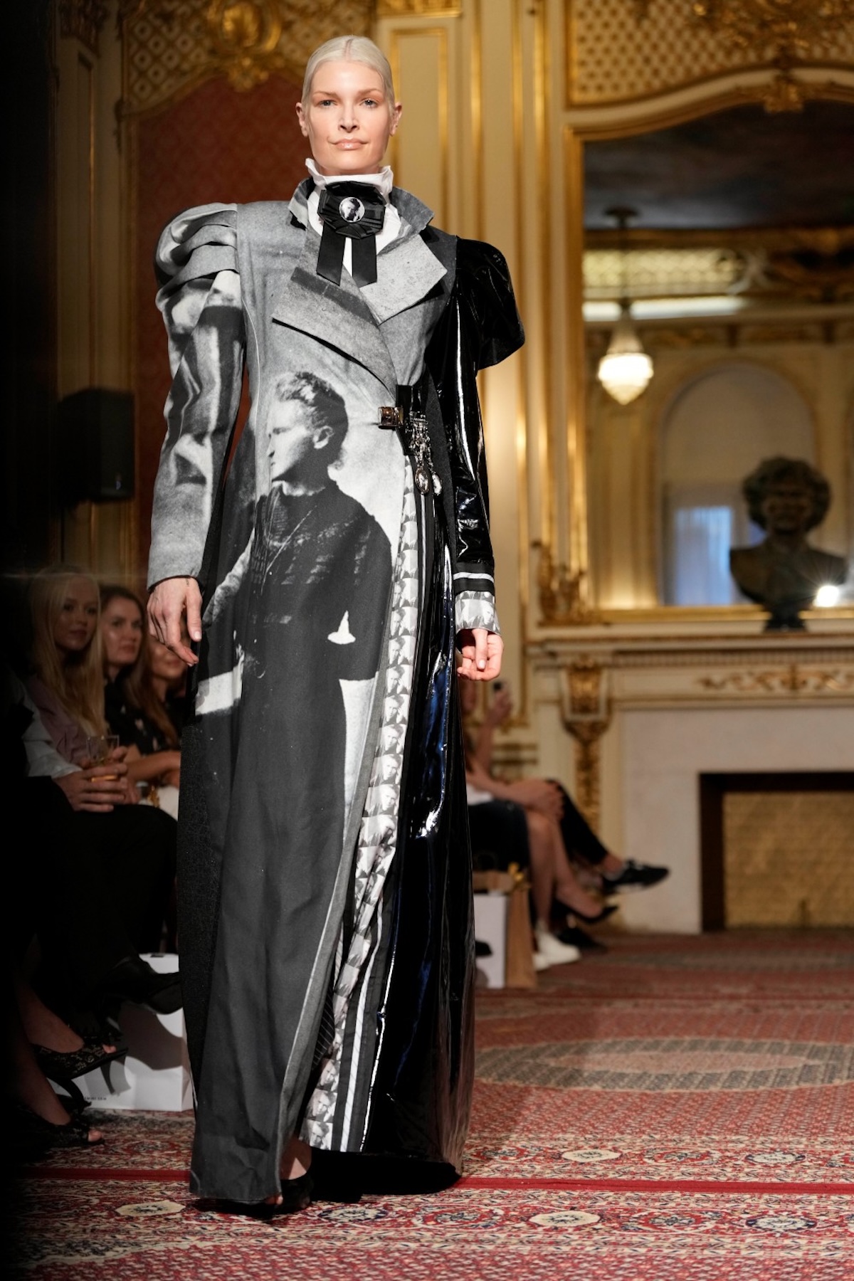 Модель у довгому пальто з художнім принтом на подіумі Польського дня моди, колекції, натхненної мистецтвом та фотографією