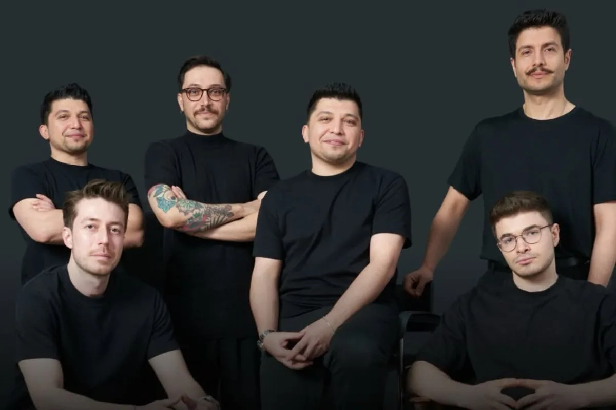 Роздрібна торгівля зі штучним інтелектом Replenit. Команда з шести чоловіків у чорних футболках позує для фотографії на нейтральному темному фоні – деякі стоять, деякі сидять, дивлячись у камеру.