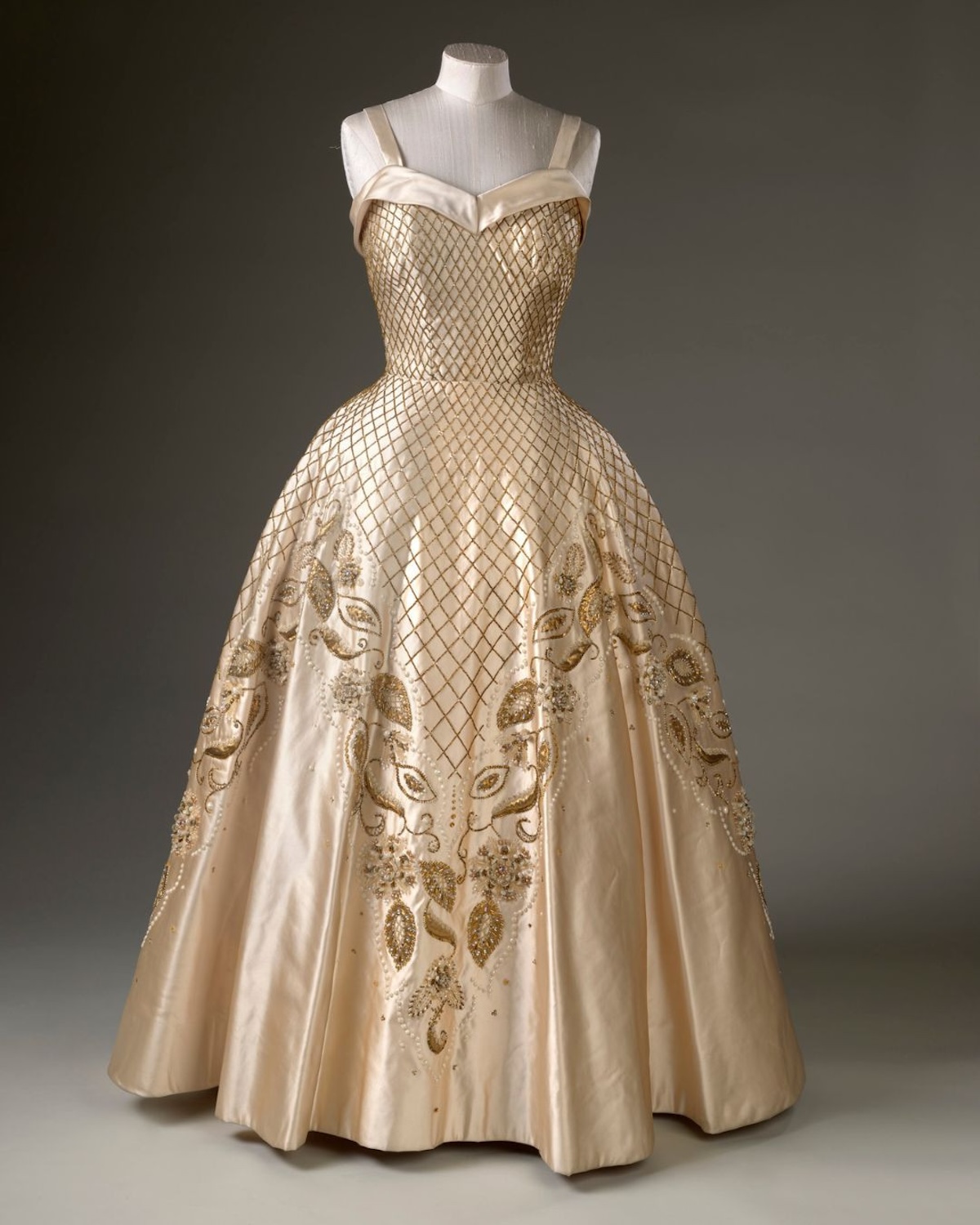 Фрагмент архівного стилю королеви Єлизавети II – помітна деталь у тканині та пошитті сукні підкреслює майстерність дизайнерів, які співпрацювали з монархом. Такі елементи, представлені на виставці в Букінгемському палаці, розкривають передісторію створення королівських костюмів та їхню важливість у формуванні образу.