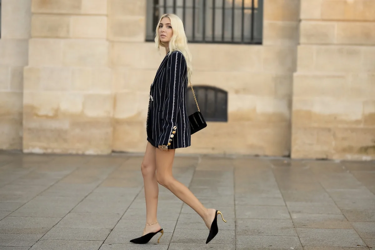 Жінка в піджаку та туфлях на підборах йде вулицею в мінімалістичному, елегантному вбранні. Такий образ ідеально підходить, коли 2 травня не є державним святом, а є звичайним днем в офісі чи на зустрічах.