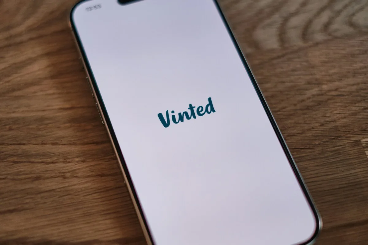 Смартфон із застосунком Vinted на екрані символізує зростаючу популярність платформи перепродажу. Фотографія натякає на фінансові результати Vinted за 2025 рік, які демонструють динамічний розвиток застосунку та зростання кількості користувачів.