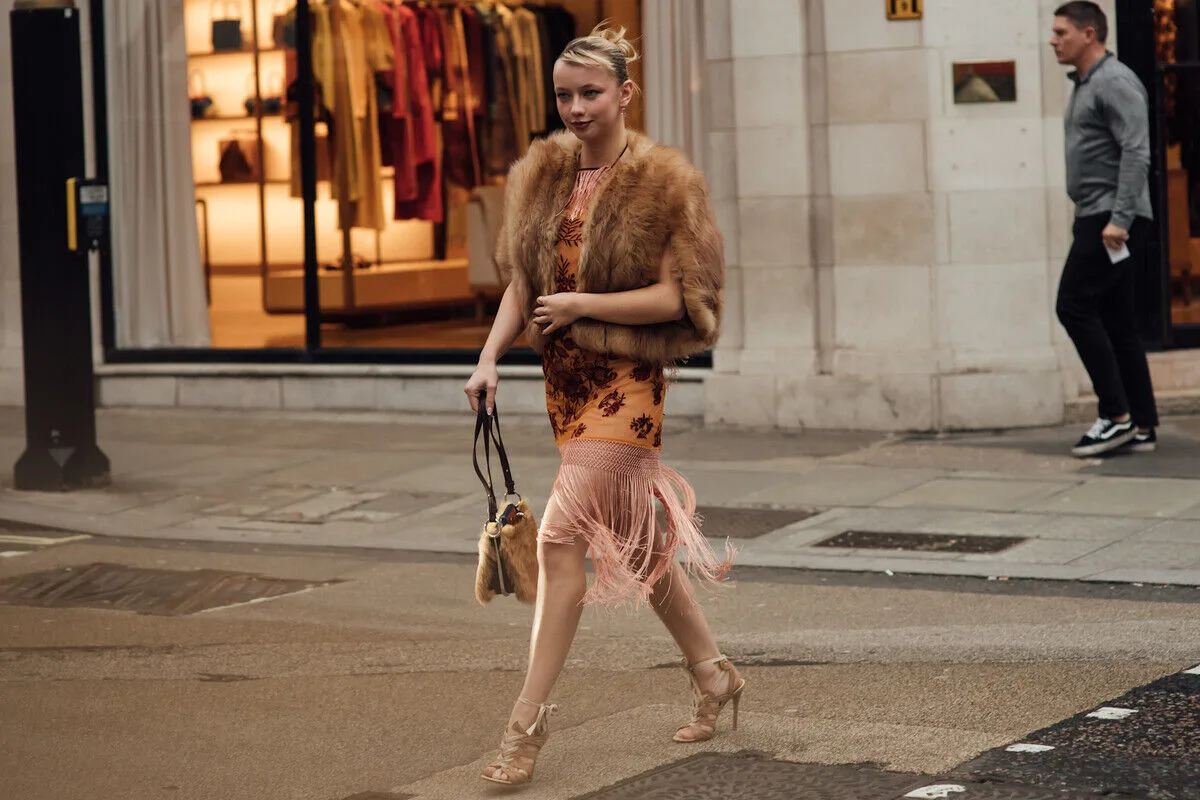 Стильно одягнена жінка на вулиці в елегантному вбранні, що відображає модні тенденції та свідоме споживання. Фотографія ідеально відображає контекст ринку перепродажу та зростаючу важливість таких платформ, як Vinted, що відповідає темі фінансових результатів Vinted за 2025 рік та зміни купівельних звичок.