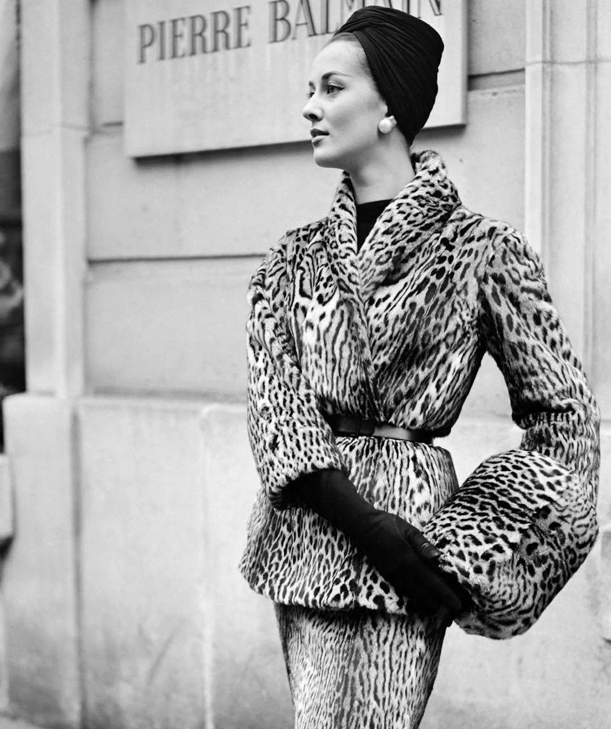 Модель в елегантному пальто з тваринним принтом перед штаб-квартирою Balmain у Парижі, повоєнні роки.