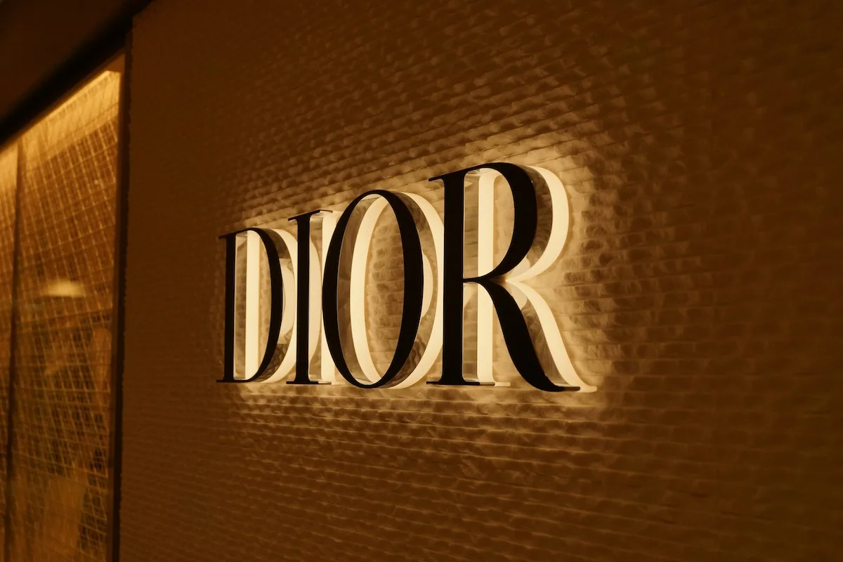 Логотип Dior підсвічується на елегантній стіні всередині преміального бутика. Бренд, що належить групі LVMH, є частиною модного сегмента, в якому у першому кварталі 2026 року спостерігалося зниження продажів.