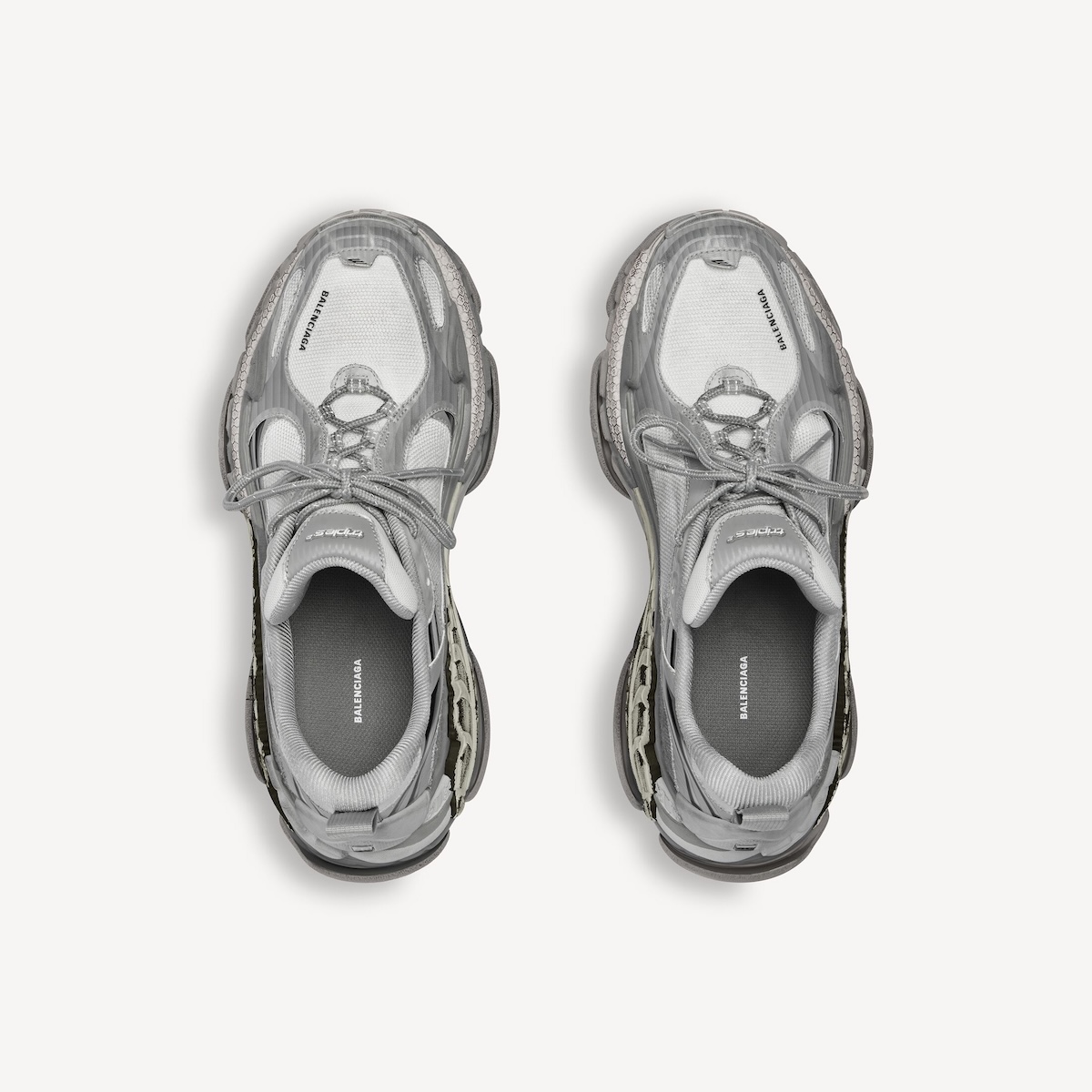 Вид зверху вниз на кросівки Balenciaga Triple S.2, що демонструє їхню складну, багатошарову конструкцію та широку підошву. Взуття розширює культову естетику Triple S, додаючи більше технічних деталей та сучасного оздоблення. Це ключовий елемент повернення бренду до кросівок як основної основи його стратегії.