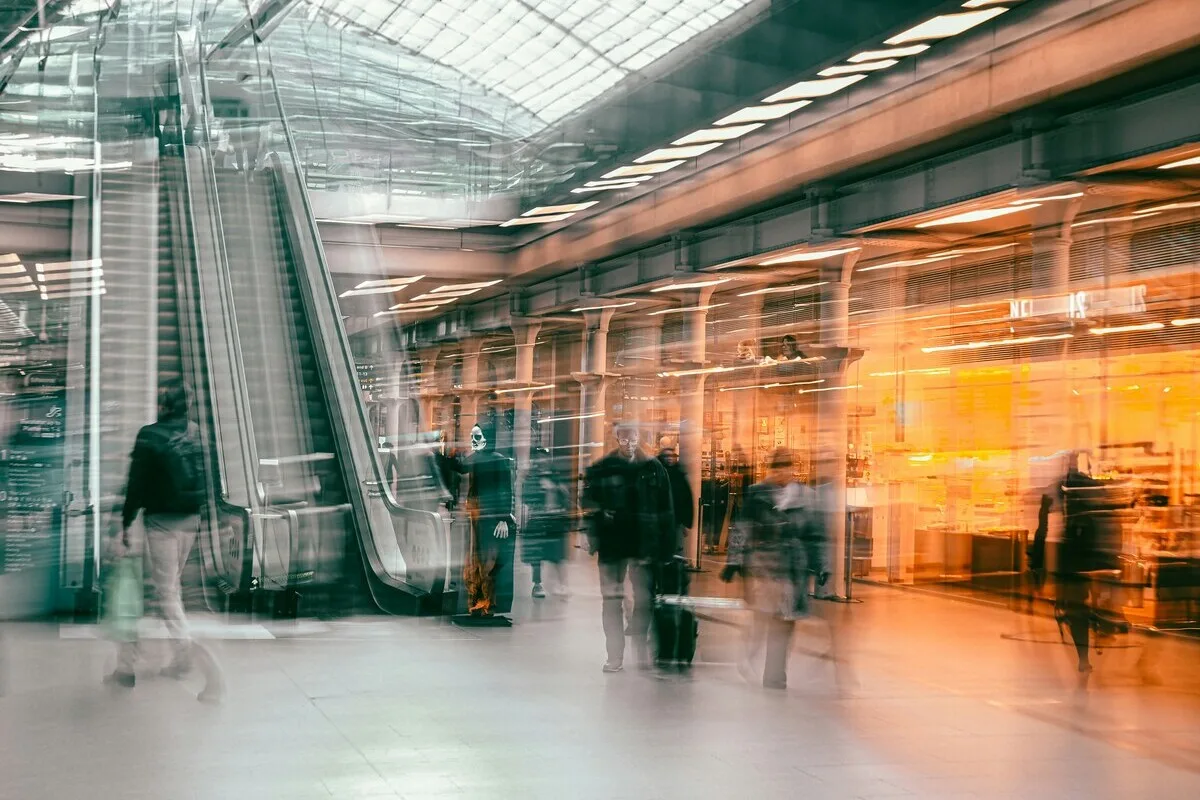 Рух транспорту в сучасному торговому центрі з видимими ескалаторами та магазинами – ілюстративне фото. Такі об'єкти, як Alfa Centrum у Гданську, описані у статті, все частіше закриваються та плануються до знесення. На їхньому місці будуються нові житлові комплекси, реагуючи на зміну потреб ринку.