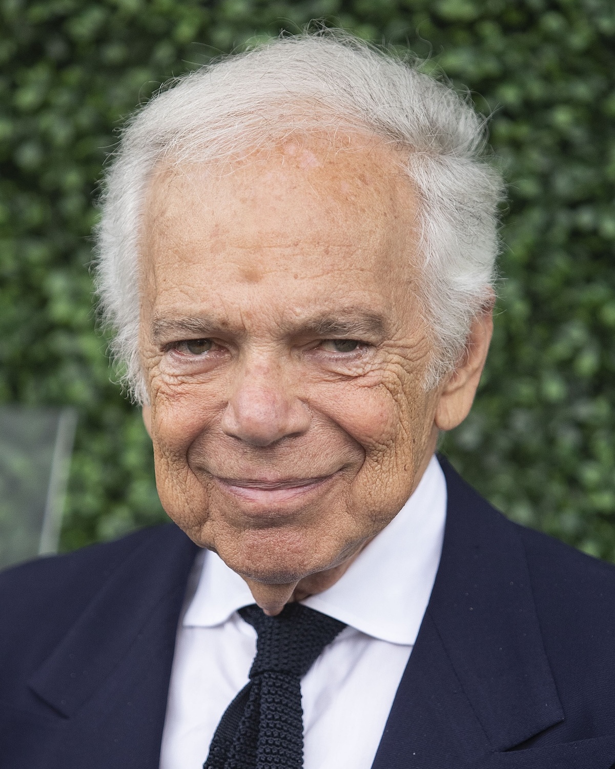 На портретній фотографії Ральф Лорен у елегантному костюмі посміхається на зеленому тлі. Як одна з найвпливовіших людей у світі за версією TIME100 2026, він десятиліттями формує глобальне сприйняття способу життя та розкоші.