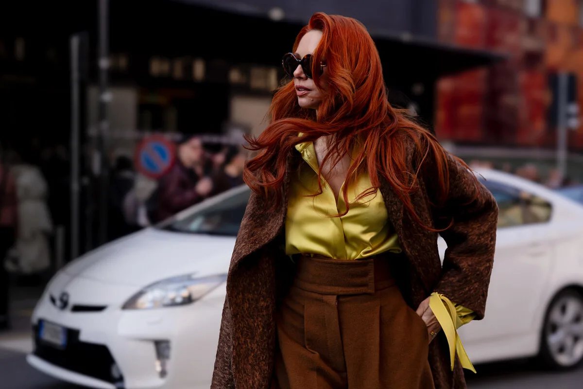 Елегантна жінка в преміальному стилі на тлі міської вулиці відображає дух покупця предметів розкоші, на якому Saks Global прагне зосередитися після реструктуризації. Нова стратегія компанії передбачає зосередження на найвибагливіших клієнтах та переосмислення досвіду покупок високого класу.