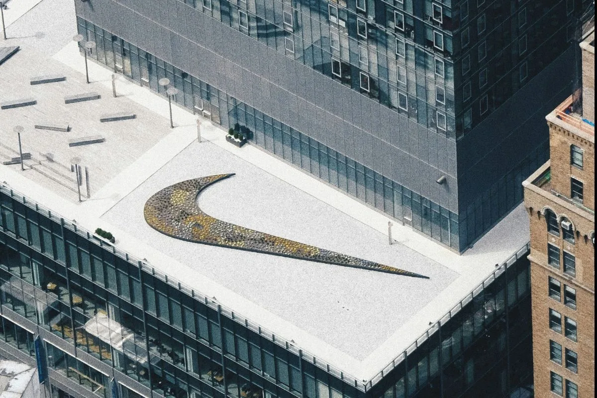 На даху сучасної офісної будівлі видно культовий логотип Nike у формі галочки. На знімку зверху видно навколишні будівлі та міський ландшафт навколо штаб-квартири компанії.