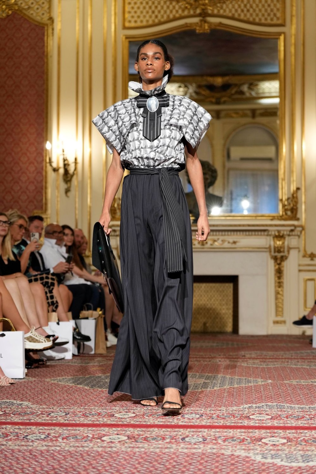 Модель у широких штанах та візерунчастій блузці на подіумі Польського дня моди, сучасна жіноча мода