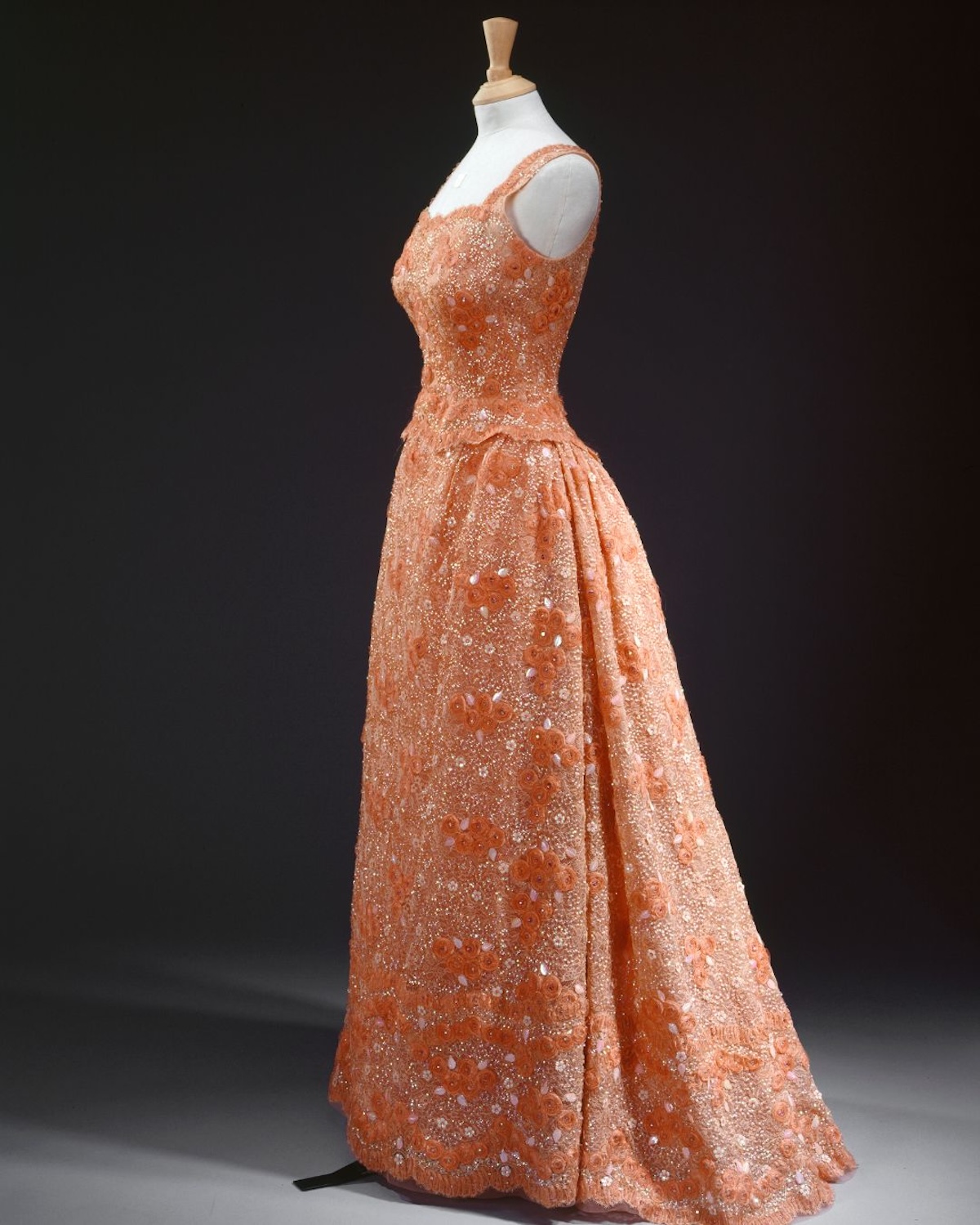 Вечірня сукня королеви Єлизавети II насиченого абрикосового відтінку прикрашена вигадливими аплікаціями та вишивкою. Сукня, представлена в Букінгемському палаці, демонструє, як колір та деталі використовувалися в стилі Єлизавети II, щоб підкреслити присутність та ранг на офіційних заходах.