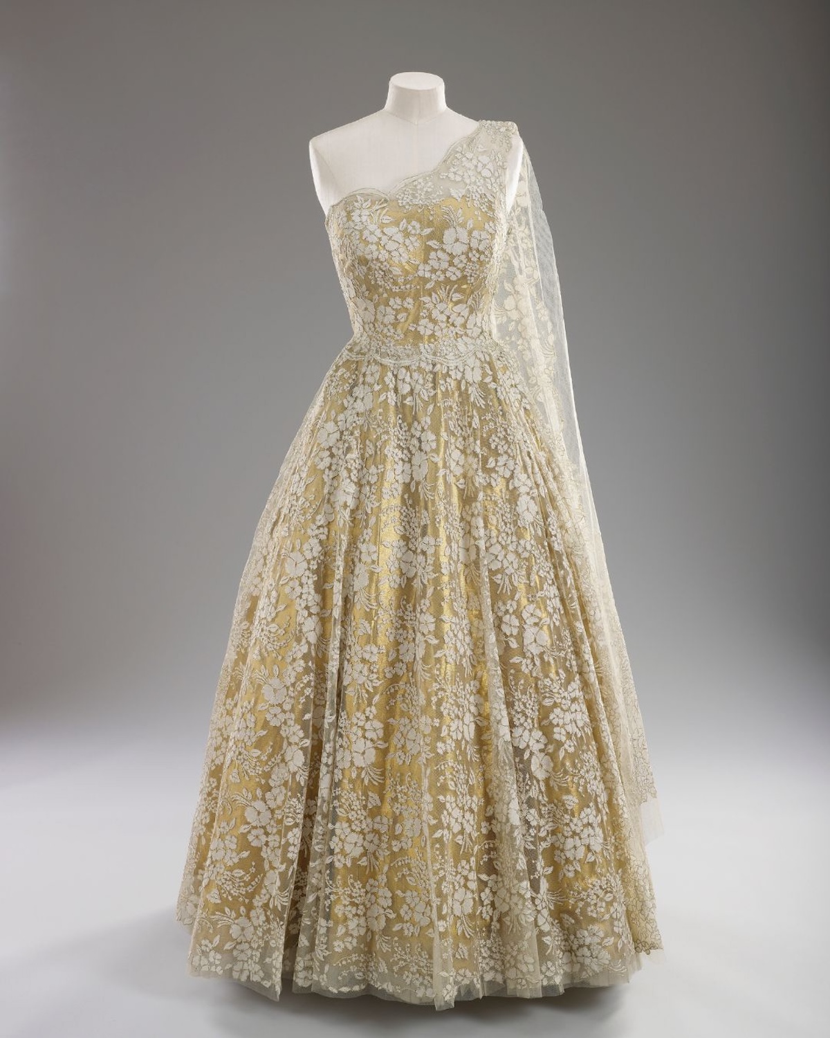 Одна з вечірніх суконь королеви Єлизавети II, багато оздоблена вишивкою та ніжним мереживом, підкреслювала церемоніальний характер королівських виступів. Виставка в Букінгемському палаці демонструє вирішальну роль тканин та майстерності у формуванні престижного іміджу Єлизавети II.