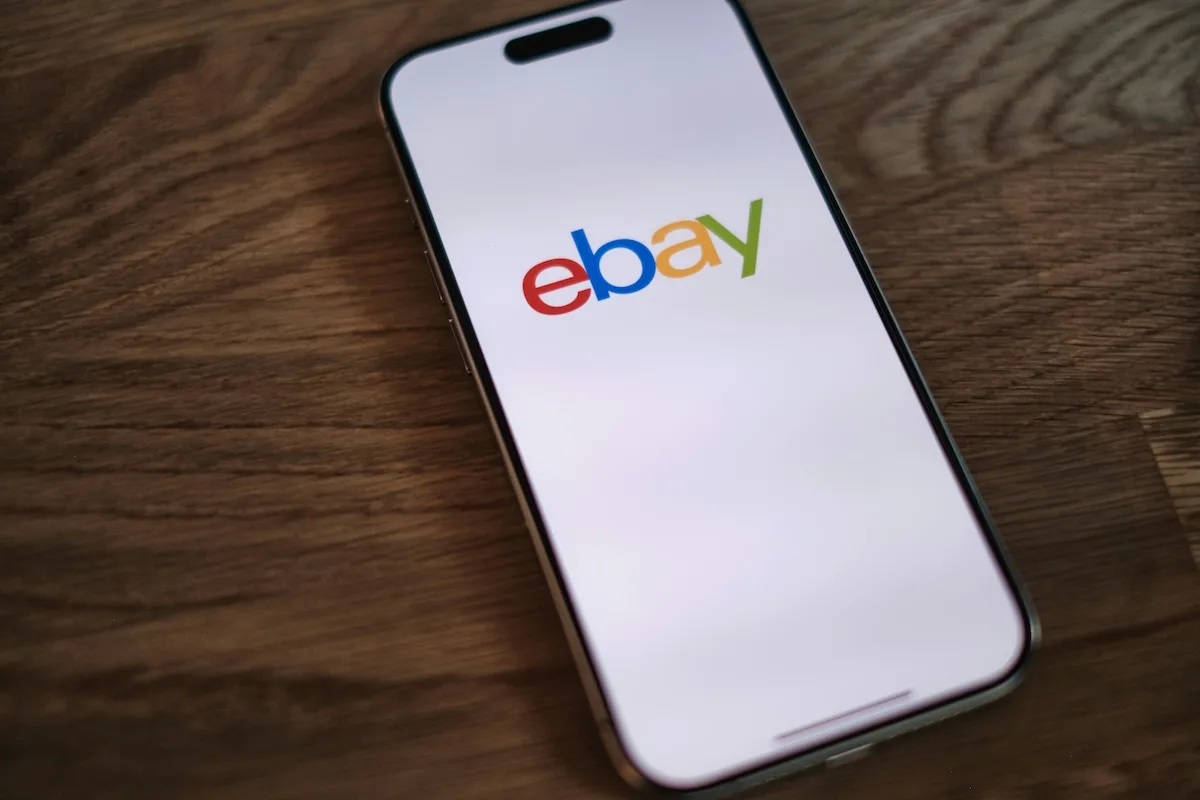Логотип eBay з'являється на екрані смартфона. GameStop хоче придбати eBay за 56 мільярдів доларів, а Раян Коен оголошує, що створює конкурента Amazon і бореться за ринок електронної комерції.