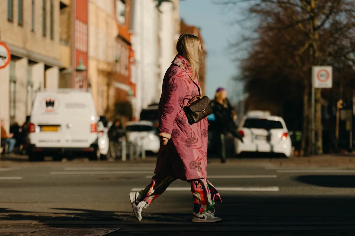 Nike закриває свій технологічний центр у Польщі. Жінка у взутті Nike переходить вулицю в європейському місті. Бренд зараз переживає одну з найбільших реструктуризацій за останні роки, включаючи закриття технологічних центрів та скорочення робочих місць у різних країнах.
