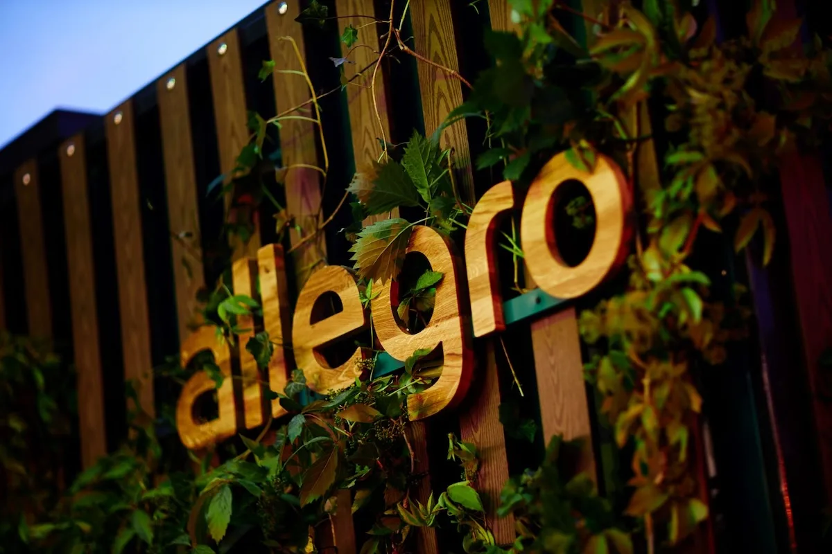Логотип Allegro оточений зеленню під час заходу бренду. Allegro розробляє нові технології штучного інтелекту та впроваджує помічника штучного інтелекту у свій мобільний додаток, трансформуючи досвід онлайн-шопінгу.
